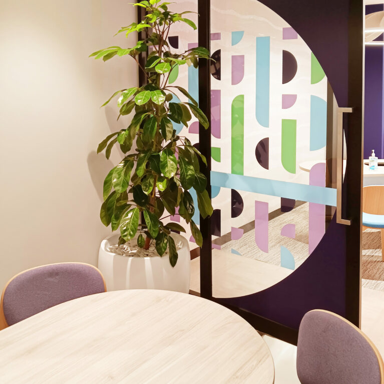 A private office with vibrant geometric decals, cozy seating, and natural accents.