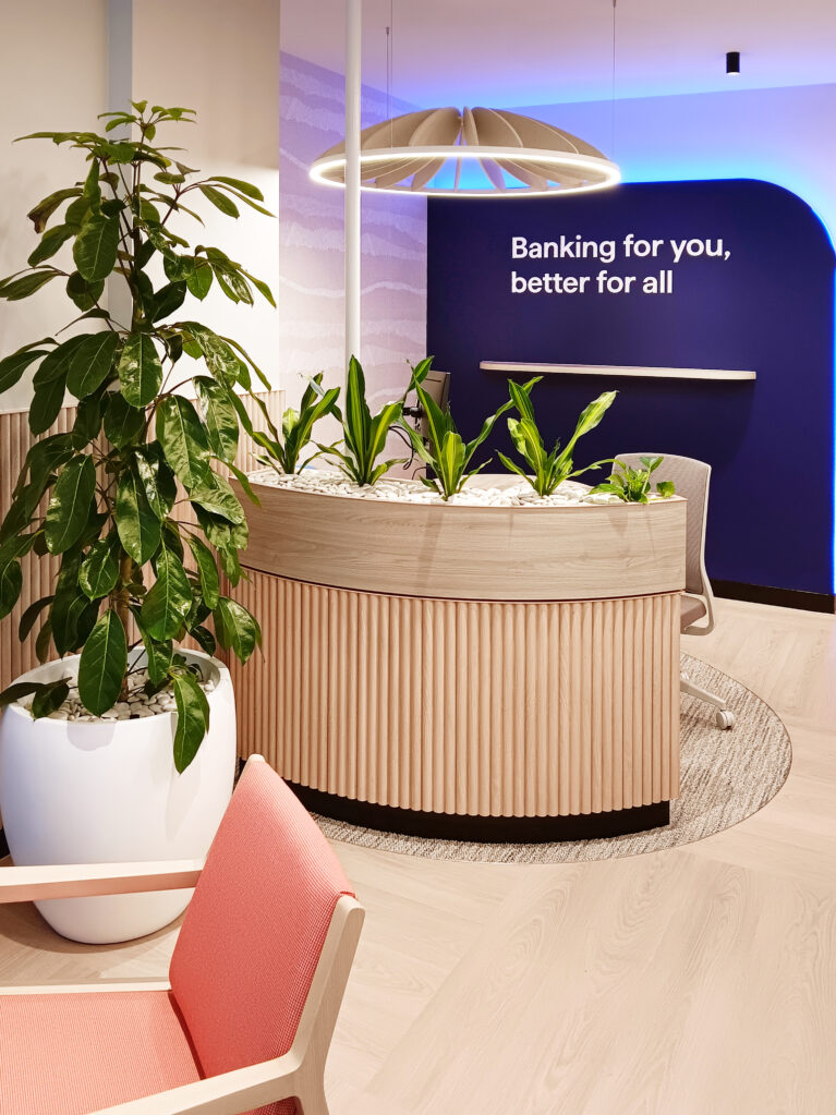 A lush planter enhances privacy and comfort at a consultation desk, with a pendant light aiding acoustics.