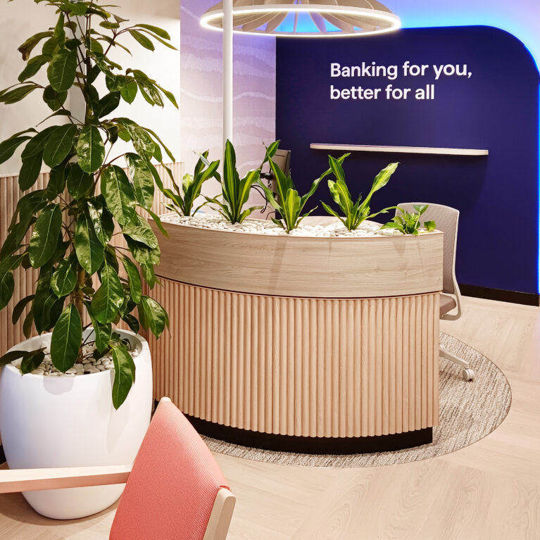 A lush planter enhances privacy and comfort at a consultation desk, with a pendant light aiding acoustics.