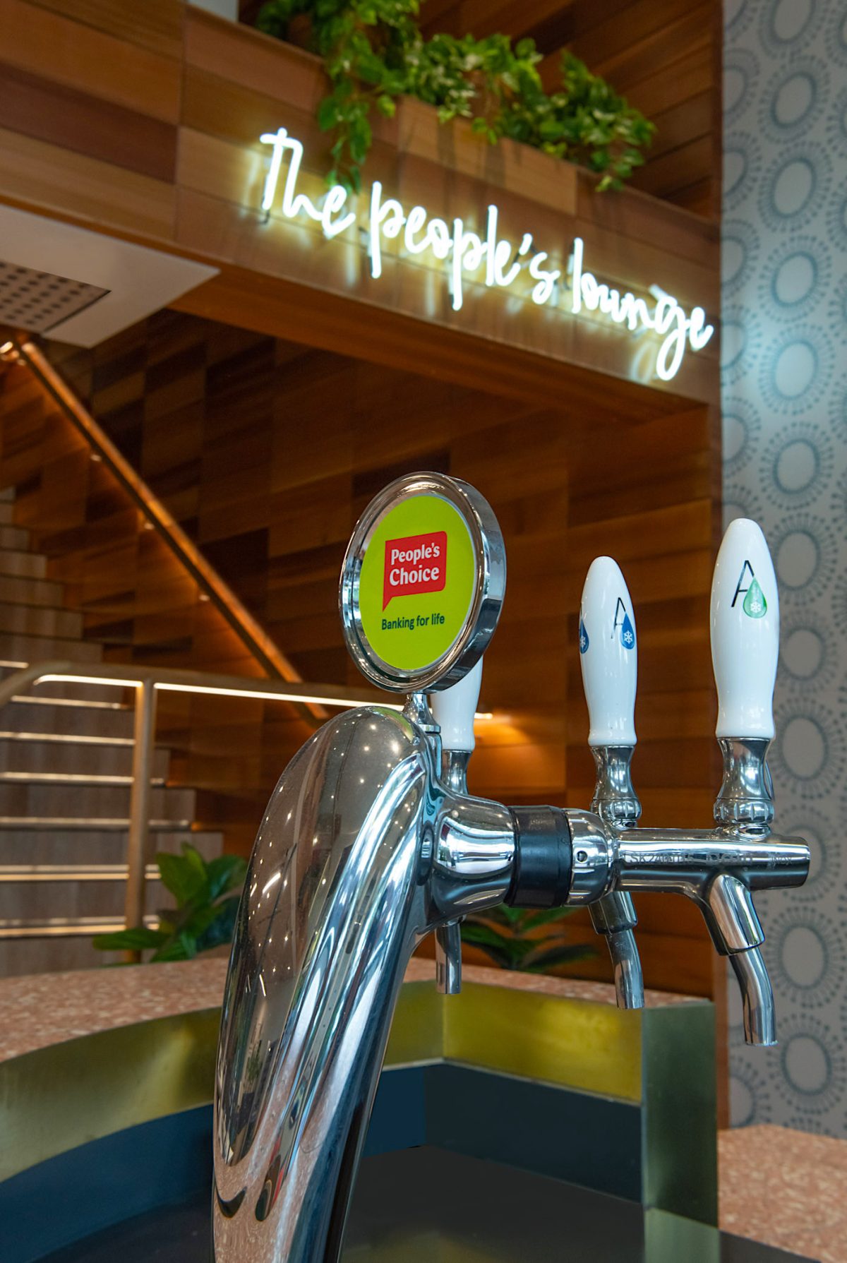 Close-up of the bar at "The People's Lounge" in People’s Choice bank, featuring a stylish triple beer tap system with chrome finishes and branded details.
