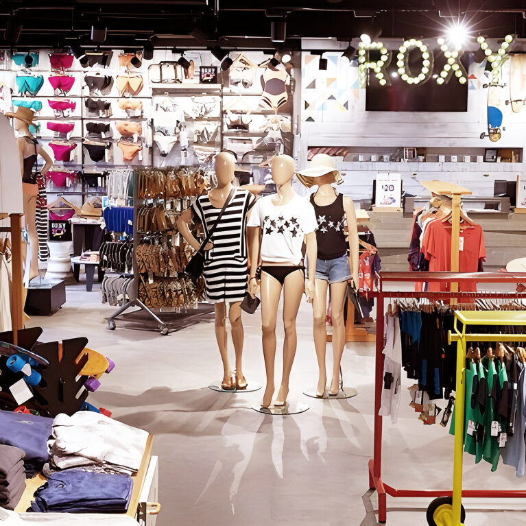 The Roxy section features bold displays with swimwear, casual outfits, and accessories, all enhanced by striking lighting and playful accents. Mannequins showcase curated looks, while the bright branding and organized layout invite customers to explore effortlessly.