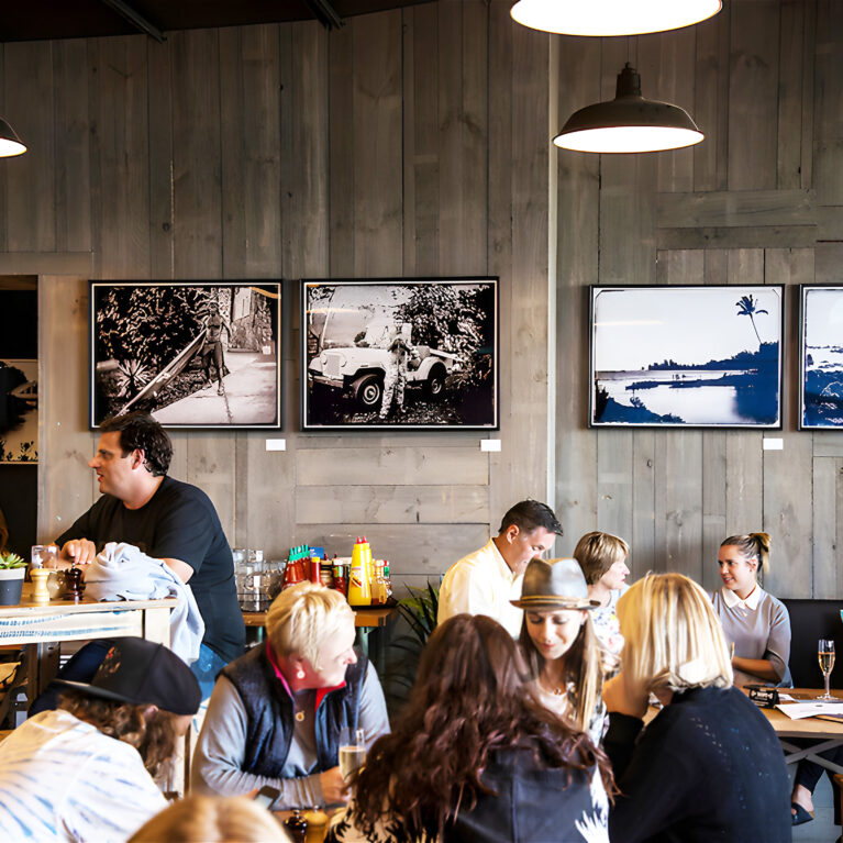 The in-store café offers a relaxed social setting, featuring reclaimed wood paneling, surf photography, and warm lighting. Guests enjoy casual dining surrounded by surf-inspired decor, making the space a natural gathering point for locals and visitors alike.