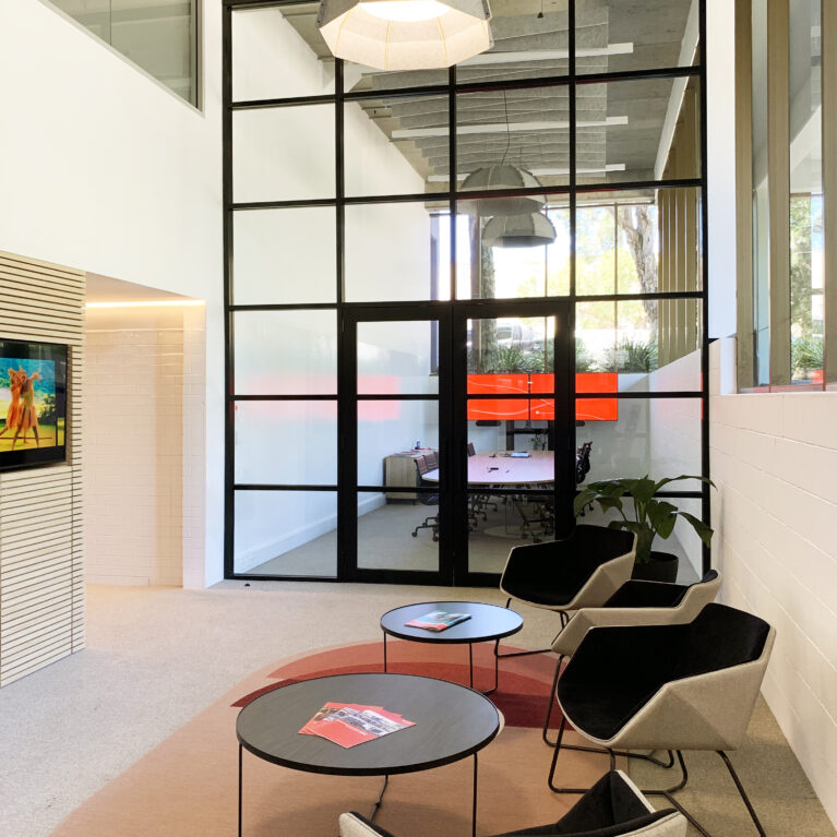 Reception area with a view into the adjacent board room, embodying a modern, open layout designed for welcoming and collaboration.