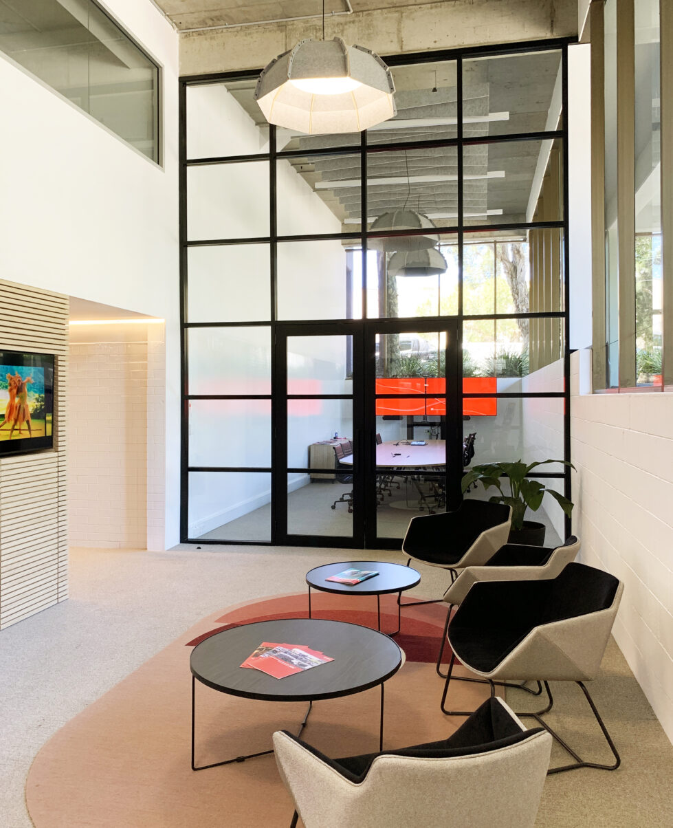 Reception area with a view into the adjacent board room, embodying a modern, open layout designed for welcoming and collaboration.