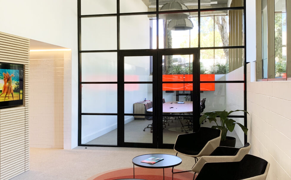 Reception area with a view into the adjacent board room, embodying a modern, open layout designed for welcoming and collaboration.