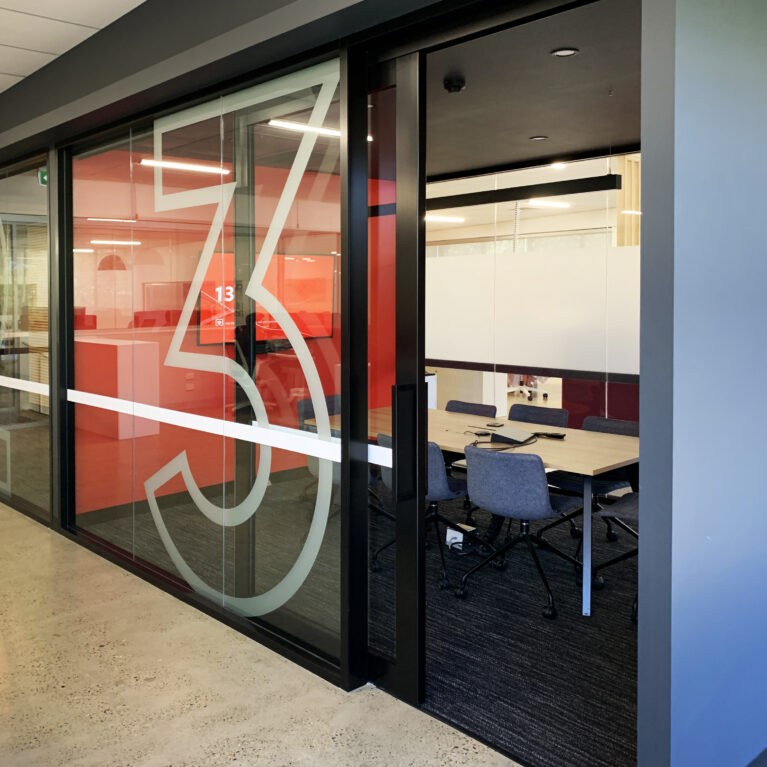 Private meeting rooms feature sleek, glass-partitioned enclosures with bold, graphic accents and a modern color palette for focused, collaborative work.