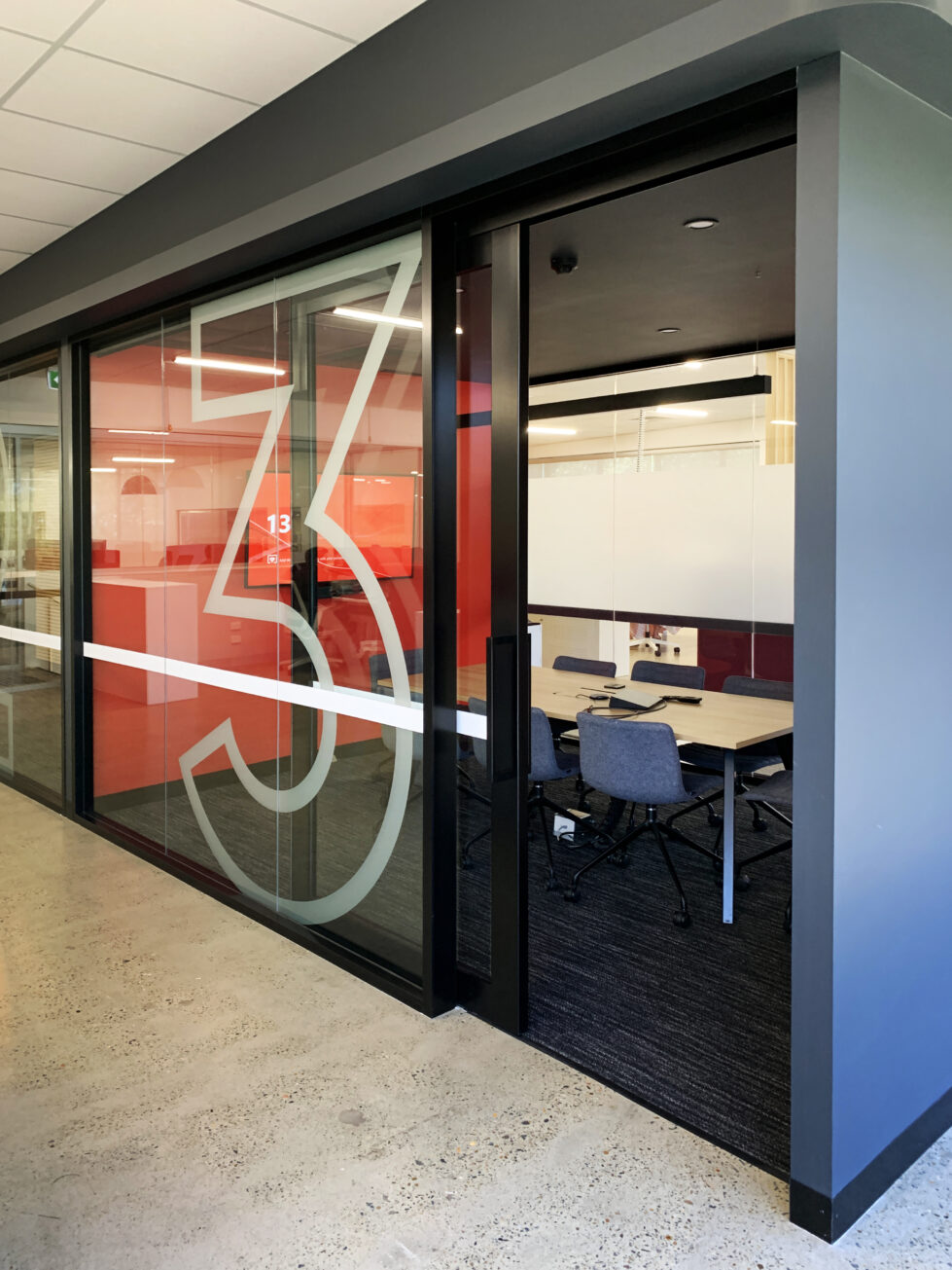 Private meeting rooms feature sleek, glass-partitioned enclosures with bold, graphic accents and a modern color palette for focused, collaborative work.