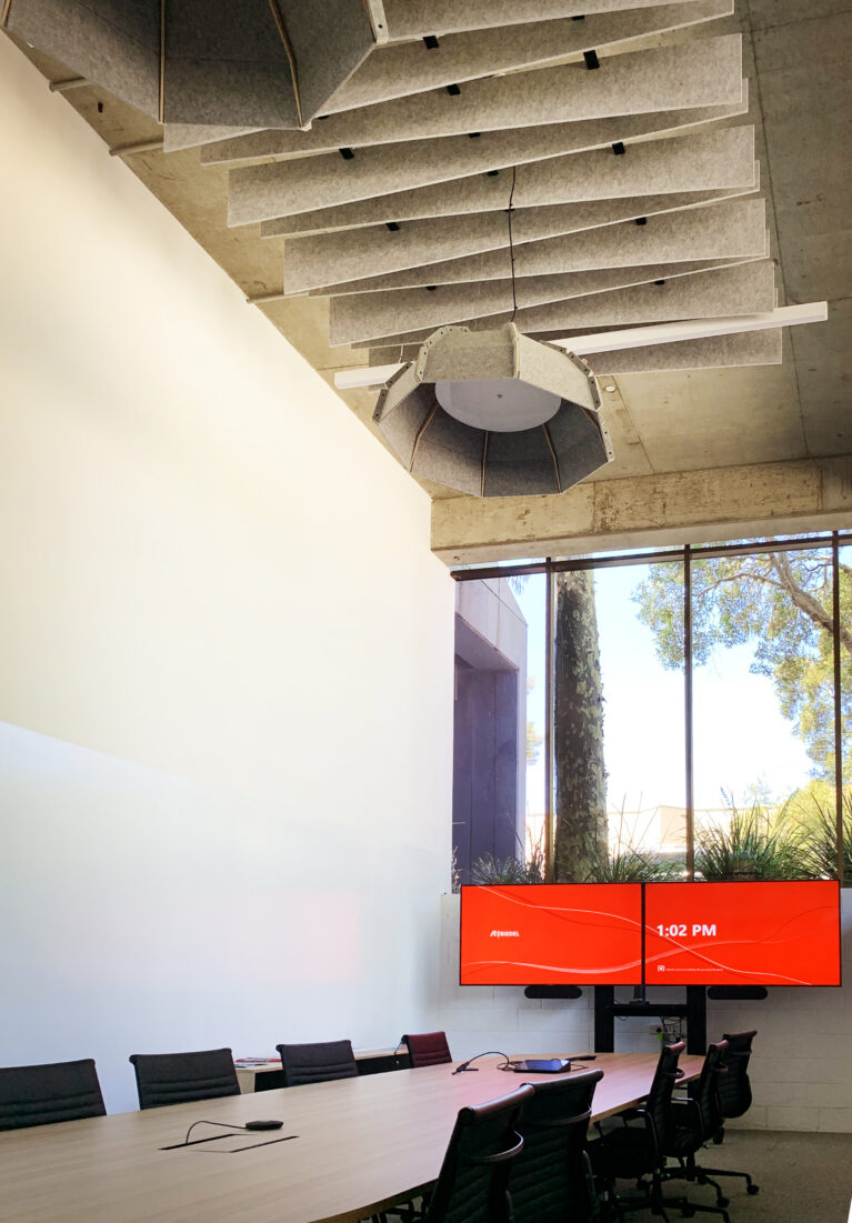 Elegant boardroom with wave-pattern acoustic ceiling and natural light.