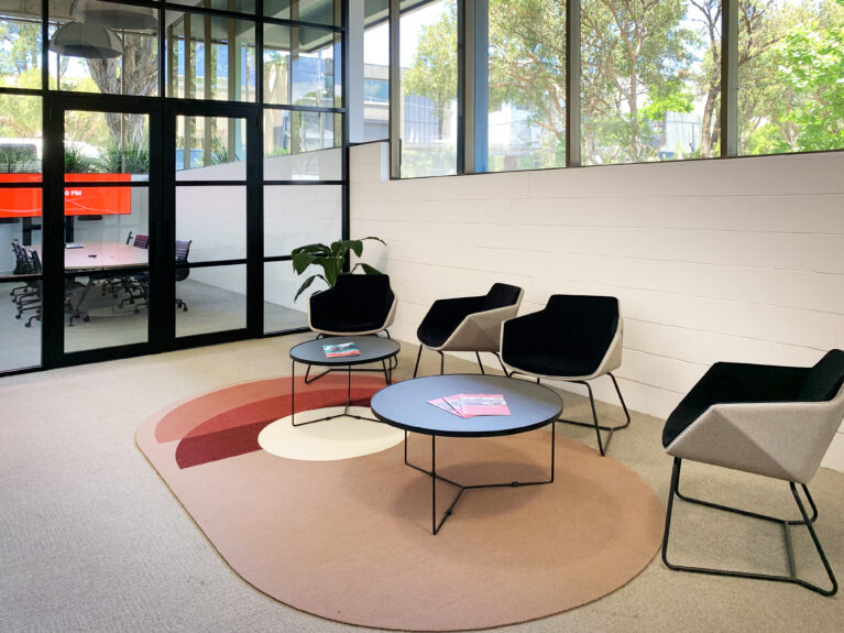 Stylish waiting area with sculpted seating, concentric-patterned rug, and abundant natural light.