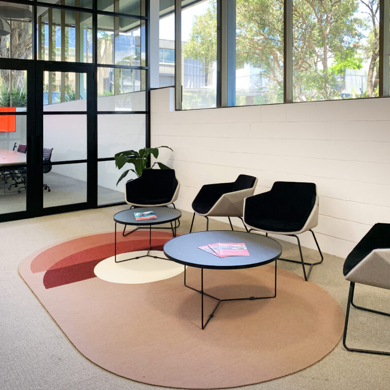 Stylish waiting area with sculpted seating, concentric-patterned rug, and abundant natural light.