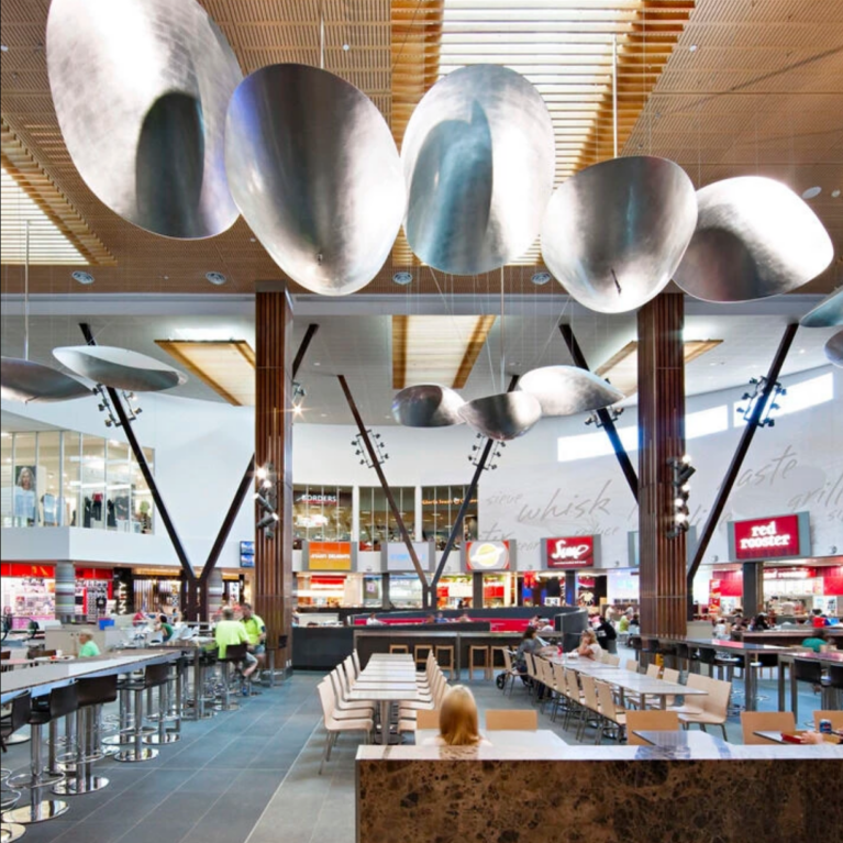 Oversized metallic pendant reflectors suspended beneath a warm timber ceiling.