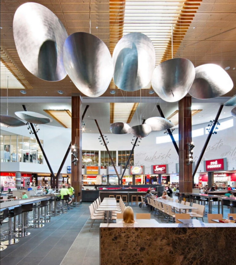 Oversized metallic pendant reflectors suspended beneath a warm timber ceiling.