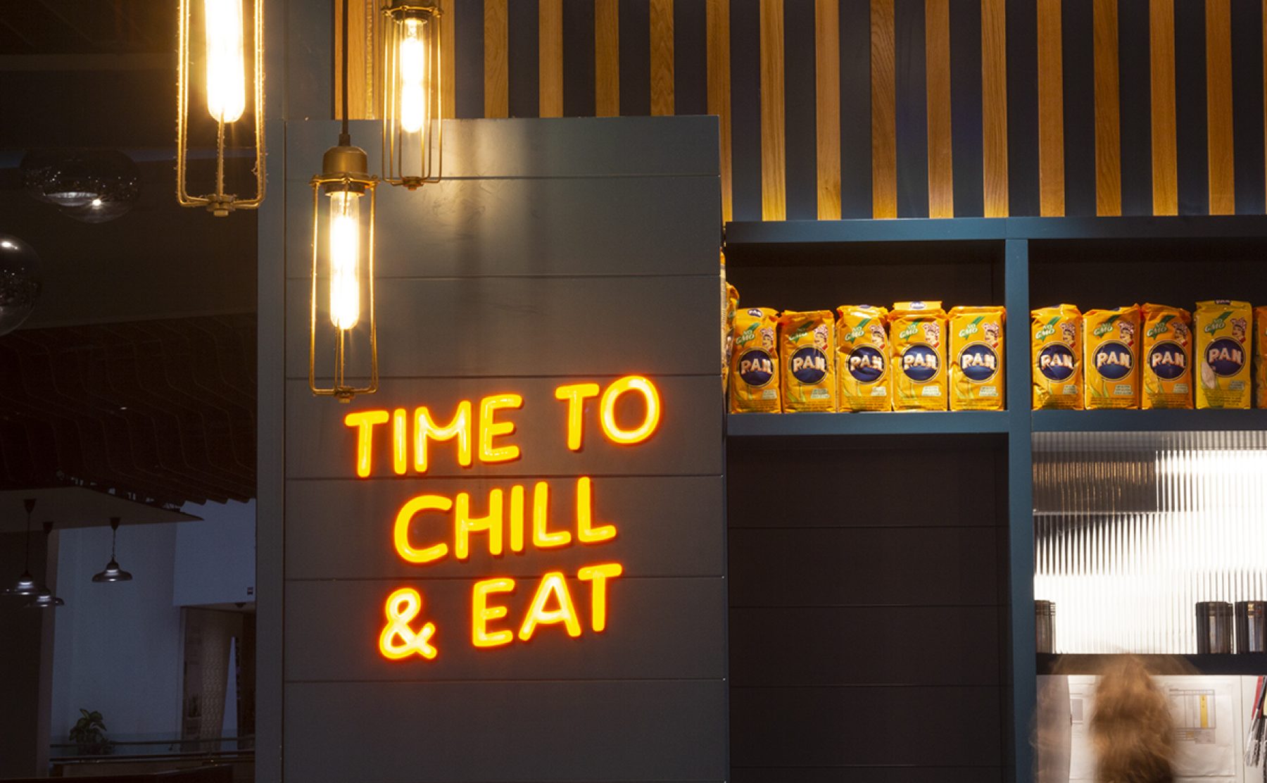 Neon brand messaging paired with industrial pendants and retail display.