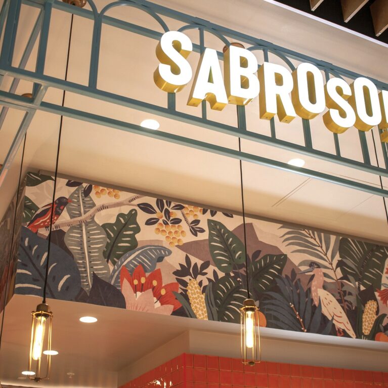 Illuminated 3D branding mounted on a light blue metal gantry structure.