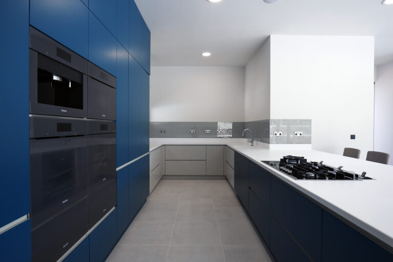 The kitchen at Skyridge balances modern functionality with elegant simplicity. Deep blue cabinetry contrasts with light finishes, creating a refined, minimalist aesthetic. High-quality materials ensure durability and ease, making this kitchen both a visual and practical centerpiece.