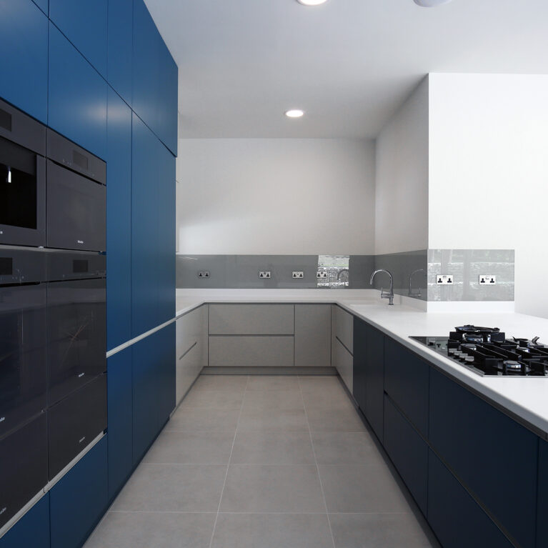 The kitchen at Skyridge balances modern functionality with elegant simplicity. Deep blue cabinetry contrasts with light finishes, creating a refined, minimalist aesthetic. High-quality materials ensure durability and ease, making this kitchen both a visual and practical centerpiece.