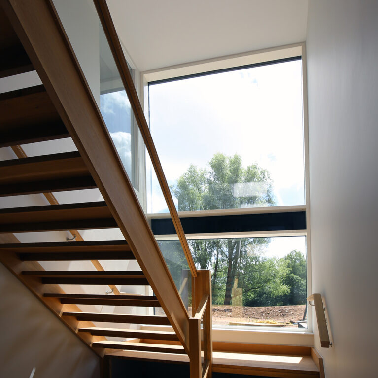 Natural light floods the stairwell through expansive glazing, illuminating the warm wooden staircase. This feature blends form and function, enhancing Skyridge’s open, airy ambiance and connecting interior spaces with views of the surrounding landscape.