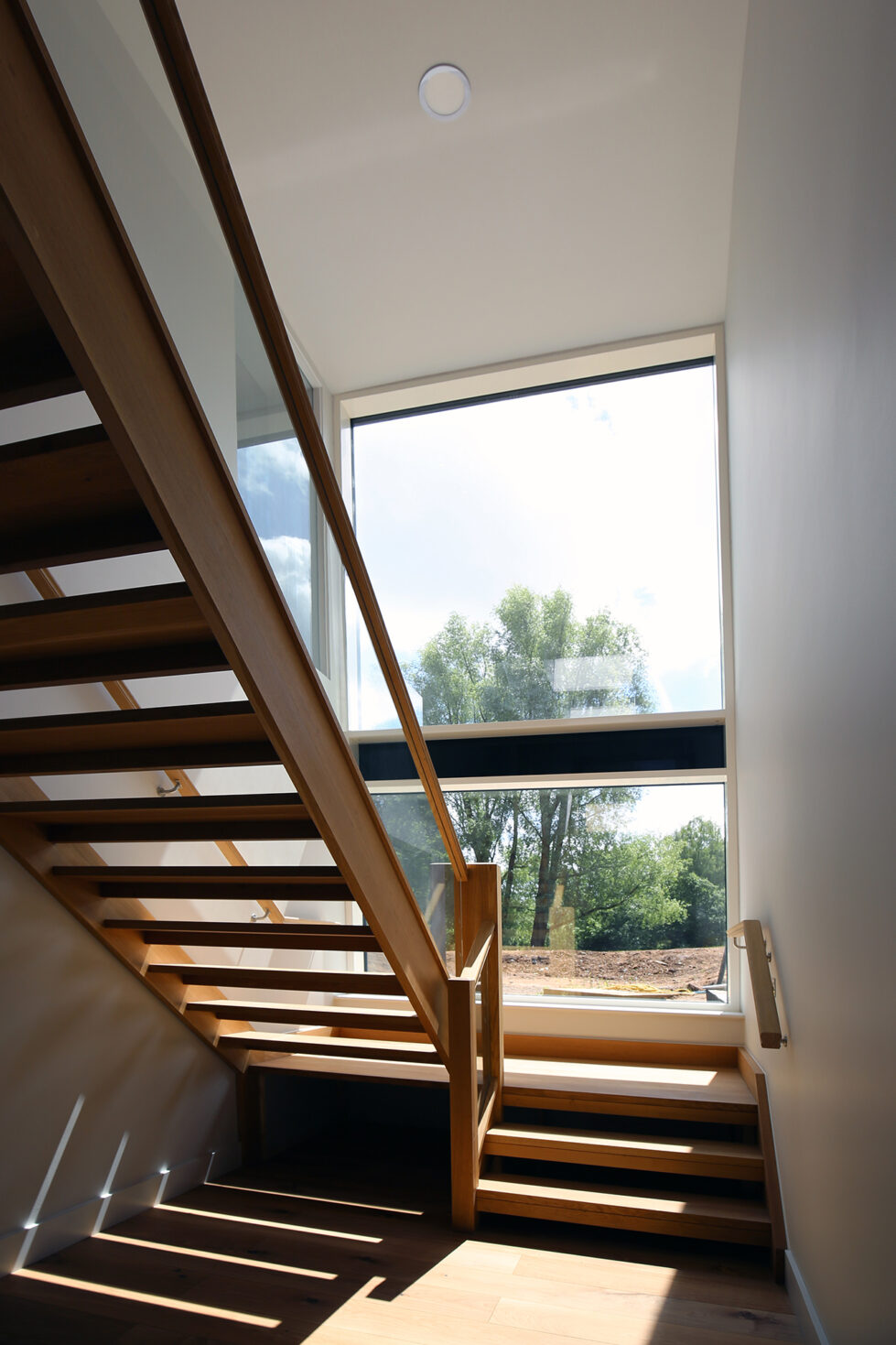 Natural light floods the stairwell through expansive glazing, illuminating the warm wooden staircase. This feature blends form and function, enhancing Skyridge’s open, airy ambiance and connecting interior spaces with views of the surrounding landscape.