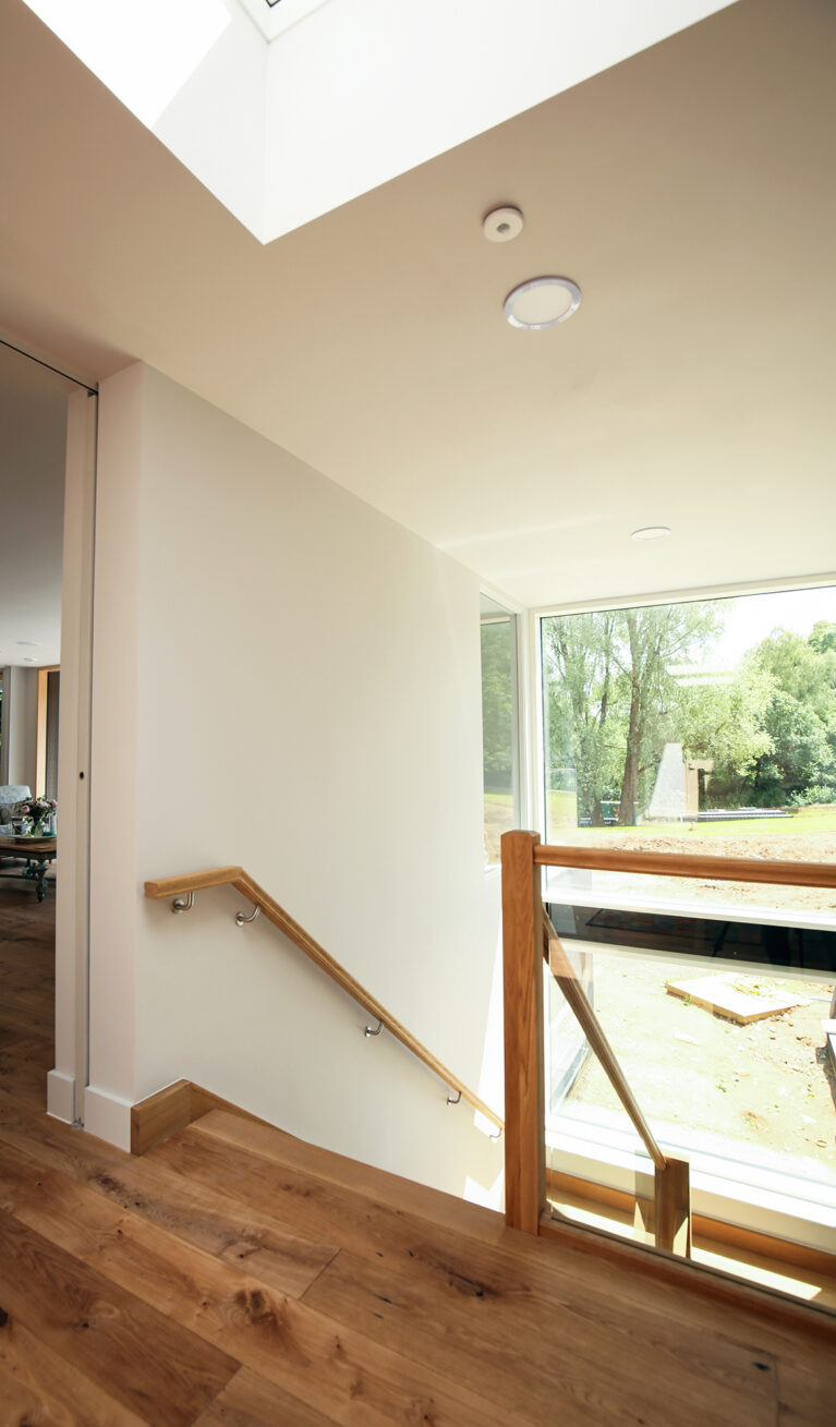 Skyridge’s stairwell features natural wood against bright, airy spaces, connecting each floor with warmth and elegance. Expansive windows bring in abundant light, enhancing the minimalist design and fostering a seamless indoor-outdoor connection.