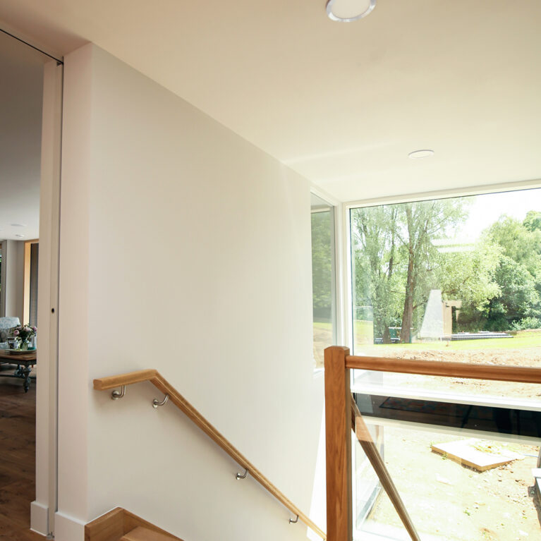 Skyridge’s stairwell features natural wood against bright, airy spaces, connecting each floor with warmth and elegance. Expansive windows bring in abundant light, enhancing the minimalist design and fostering a seamless indoor-outdoor connection.