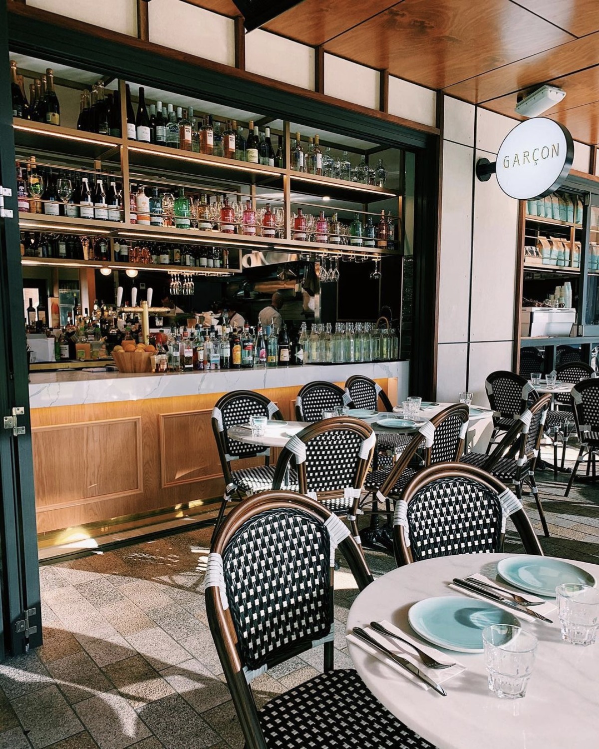 The Garçon bar, a chic cafe with elegant marble-topped counters and inviting indoor-outdoor seating.