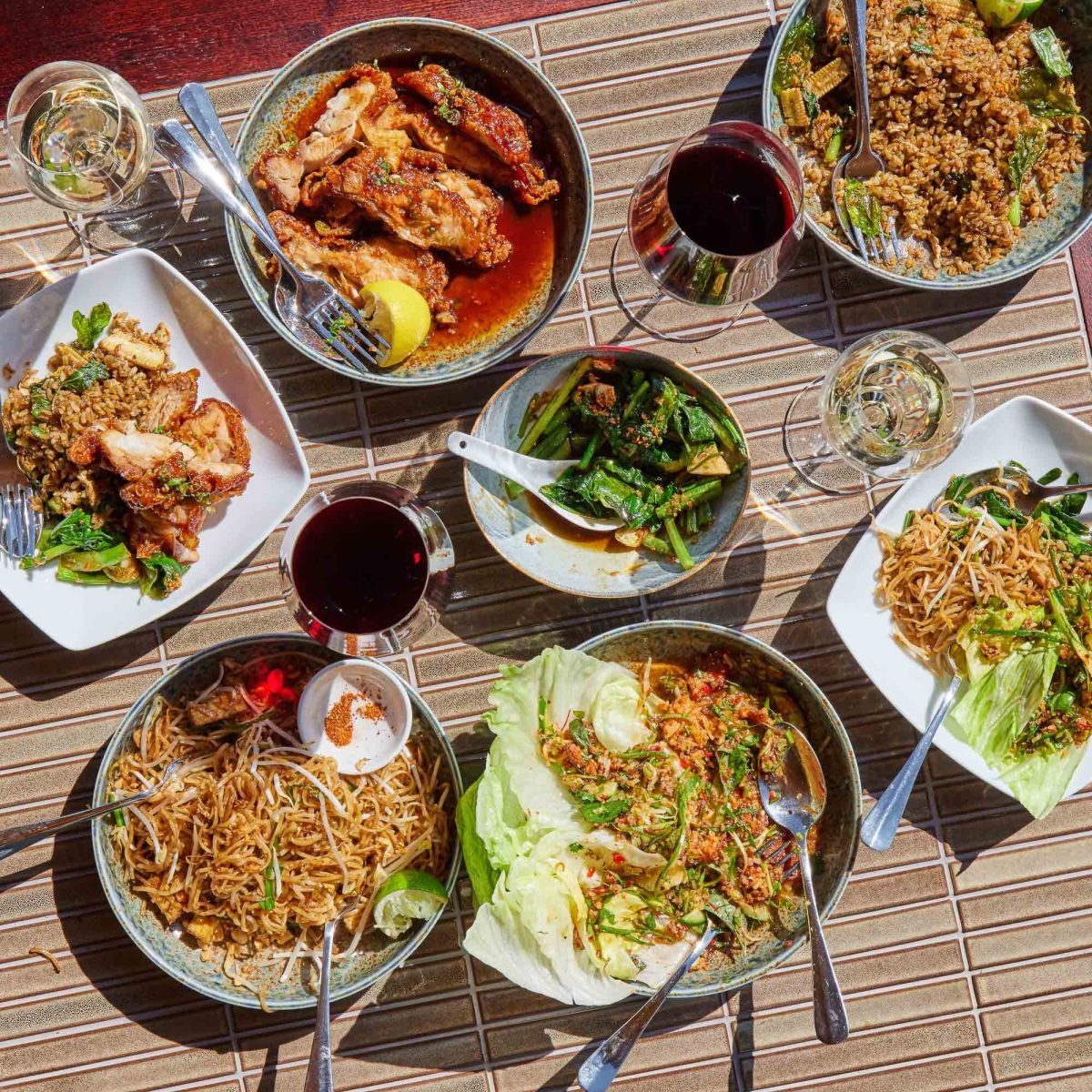 An inviting array of Thai dishes at Sugarlane, set on a woven table mat, capturing a casual, communal dining experience.
