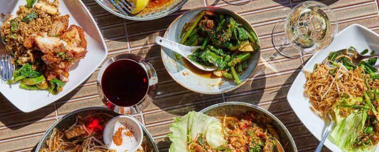 An inviting array of Thai dishes at Sugarlane, set on a woven table mat, capturing a casual, communal dining experience.
