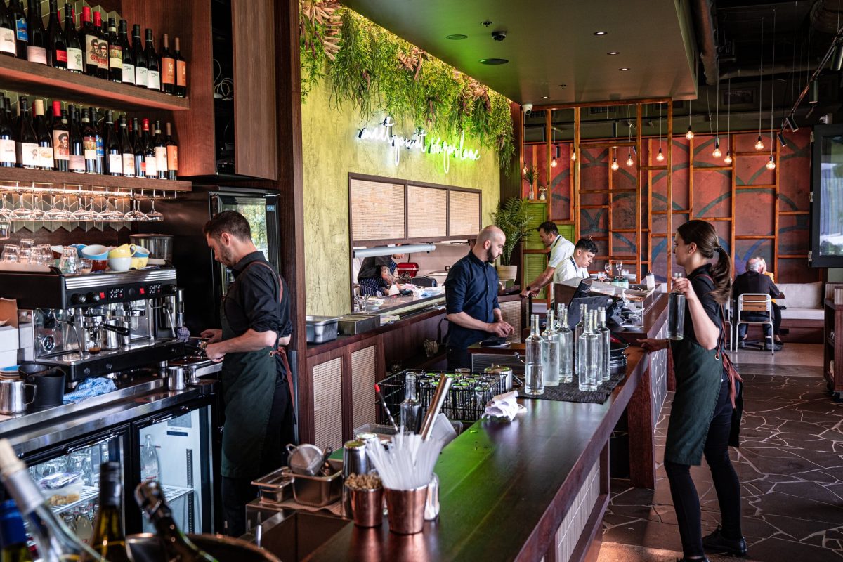 The Sugarlane Bar, featuring a warm, inviting design with wood paneling, greenery, and Edison-style lighting.