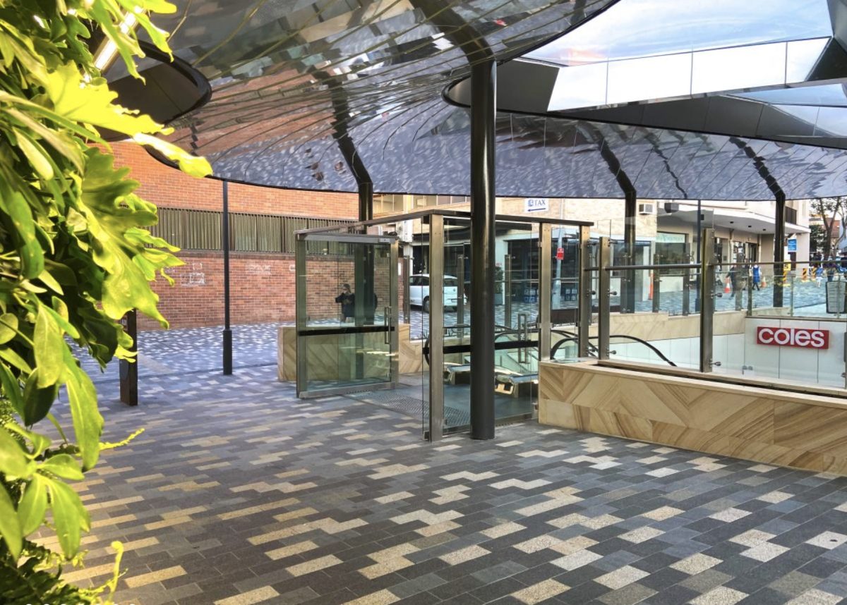 The Scott Carver plaza with escalator access, featuring modern paving, greenery, and a sleek canopy.