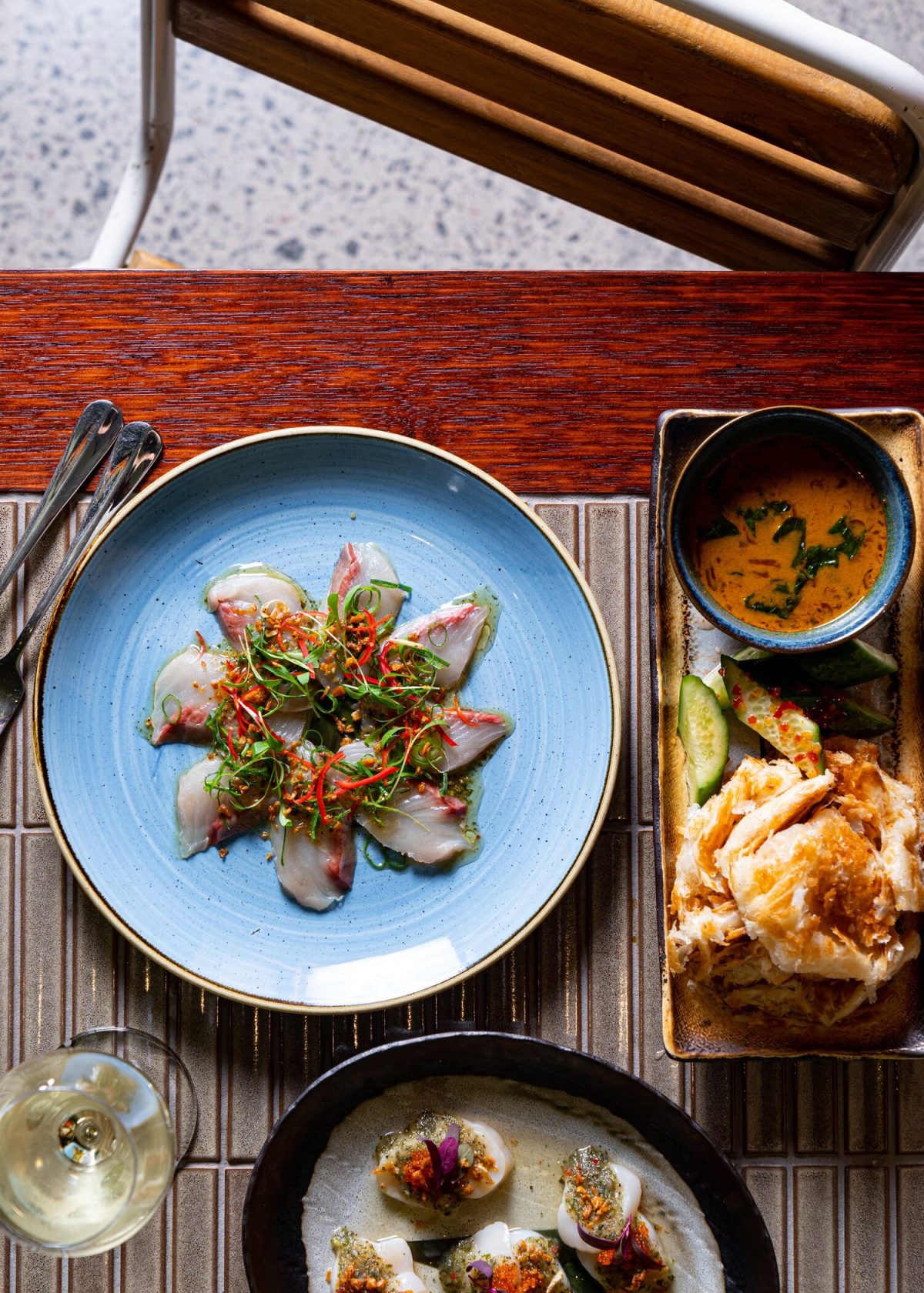 A beautifully arranged dining table with a mix of textures, colors, and carefully curated tableware, adding to the ambiance of a modern restaurant.