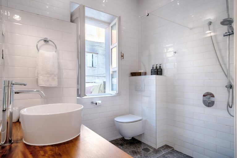A sleek bathroom with a modern walk-in shower, clean white subway tiles, and luxurious finishes. Encaustic tiles and the Methven Aurajet Aio showerhead add artisanal charm and contemporary functionality.