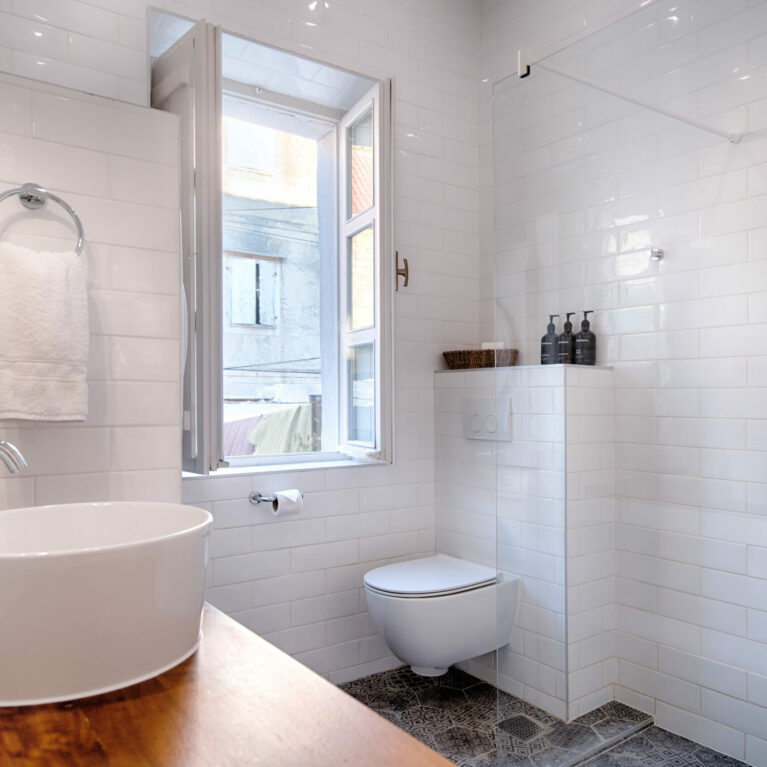 A sleek bathroom with a modern walk-in shower, clean white subway tiles, and luxurious finishes. Encaustic tiles and the Methven Aurajet Aio showerhead add artisanal charm and contemporary functionality.