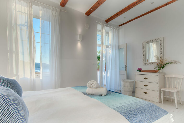 An elegant corner with vintage-inspired furnishings and modern simplicity. Carved wooden accents and light curtains frame a serene and functional space.