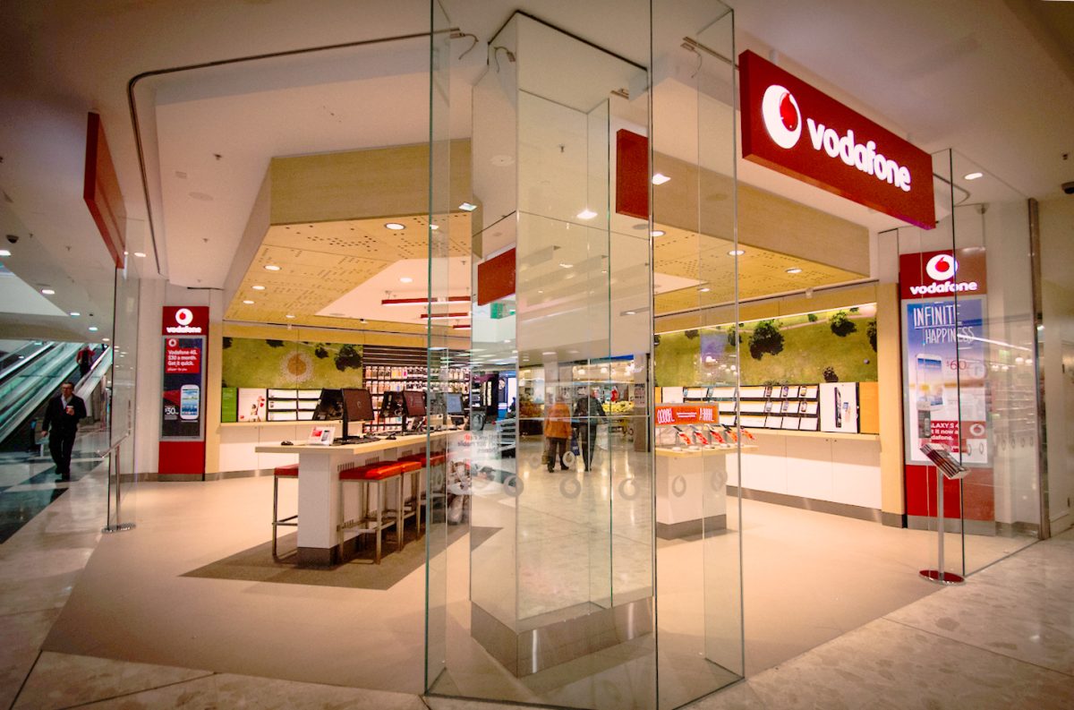 A Vodafone store within a bustling shopping mall, featuring a glass storefront and contemporary, open-plan design.