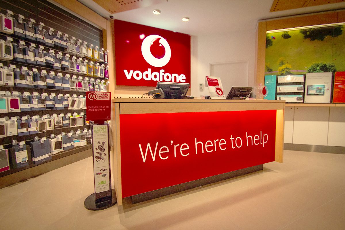 Another view of the Vodafone welcome desk, featuring vibrant signage and neatly arranged product displays.