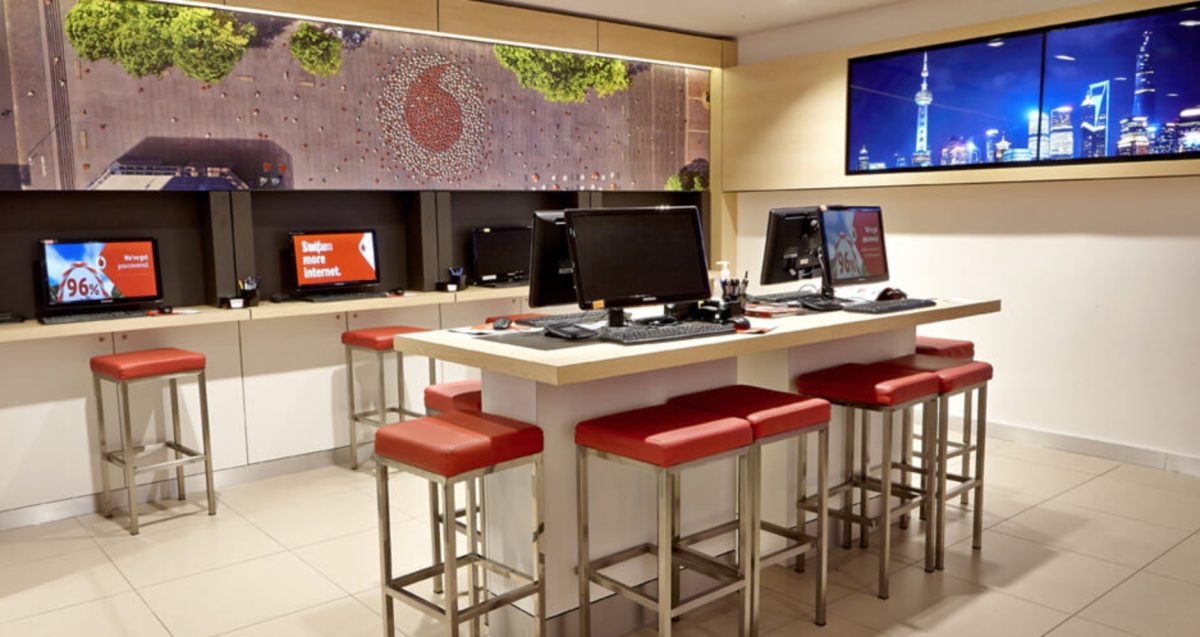 The customer service desk at Vodafone, featuring a modern design with interactive computer workstations, bold accent colors, and a visually engaging mural.