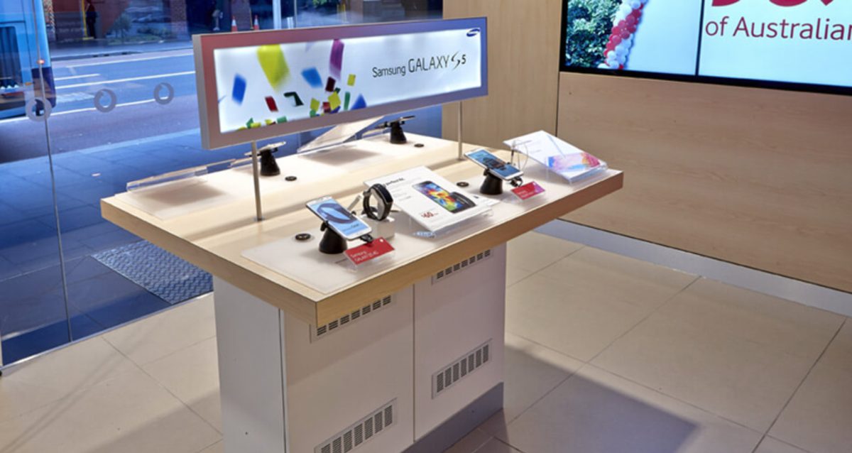 A Samsung phone display kiosk in a Vodafone Australia store, featuring Galaxy models, interactive screens, and vibrant marketing visuals.