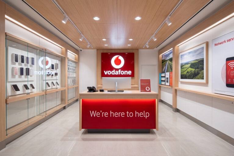 Retail store interior, timber ceiling paneling, illuminated service desk, brand logo wall, glass display cabinets, recessed track lighting, commercial telecommunications fitout.